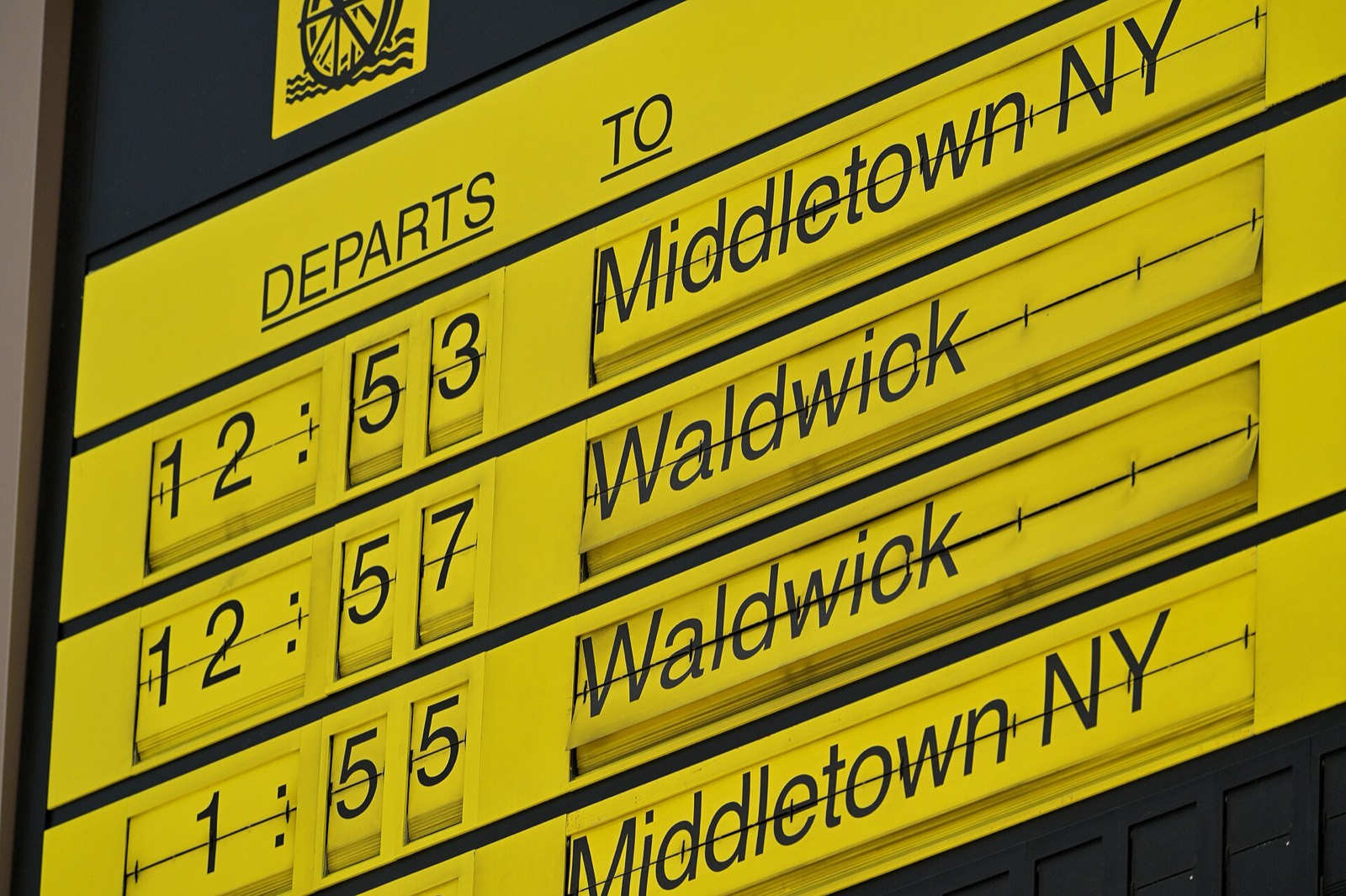 A yellow Solari split-flap departure board in a station